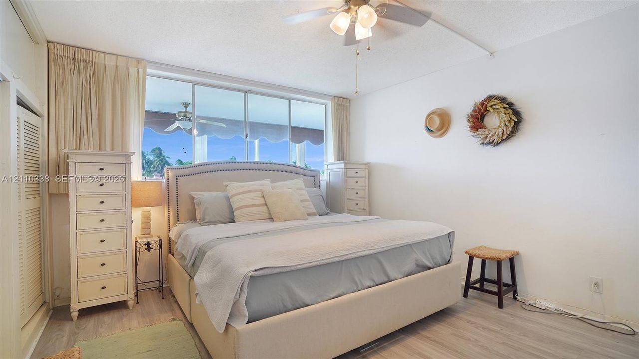 Wall-to-wall windows, wood-finish flooring, ceiling fan with integrated lighting, and louvered closet doors