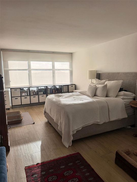 Room featuring wood-finish flooring and a multi-pane window with a neutral roller shade