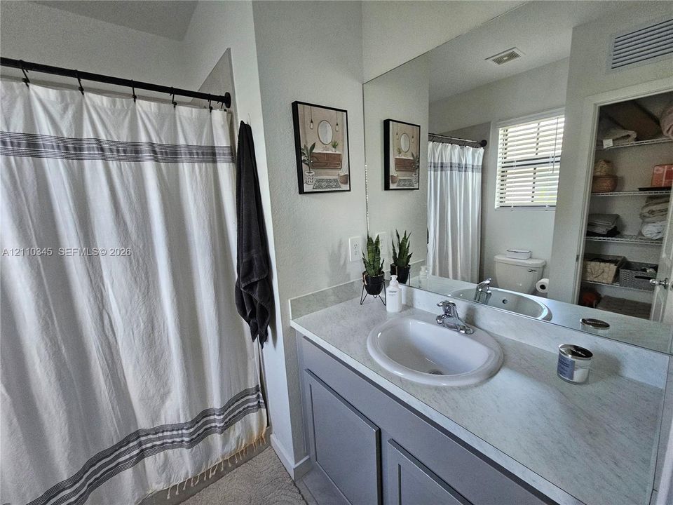Bathroom featuring a vanity with shaker-style cabinetry, an integrated sink with a chrome faucet, a stone-finish countertop, and a full-width wall mirror