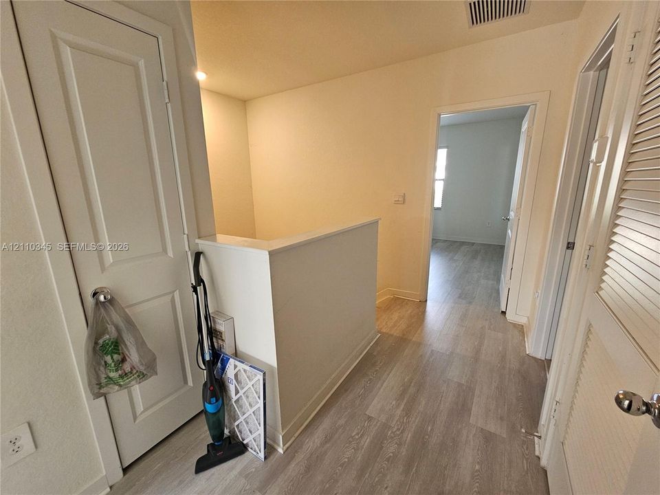 Wood-finish flooring throughout, featuring interior paneled doors, a louvered closet door, and a half-height partition wall