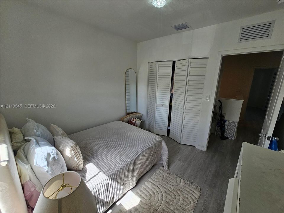 Room featuring light wood-finish flooring and a built-in closet with white louvered bifold doors