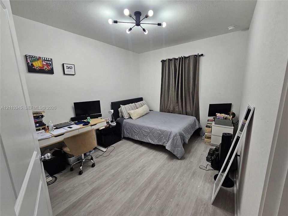 Wood-finish flooring, matte black multi-arm sputnik-style ceiling light fixture, and neutral wall tones