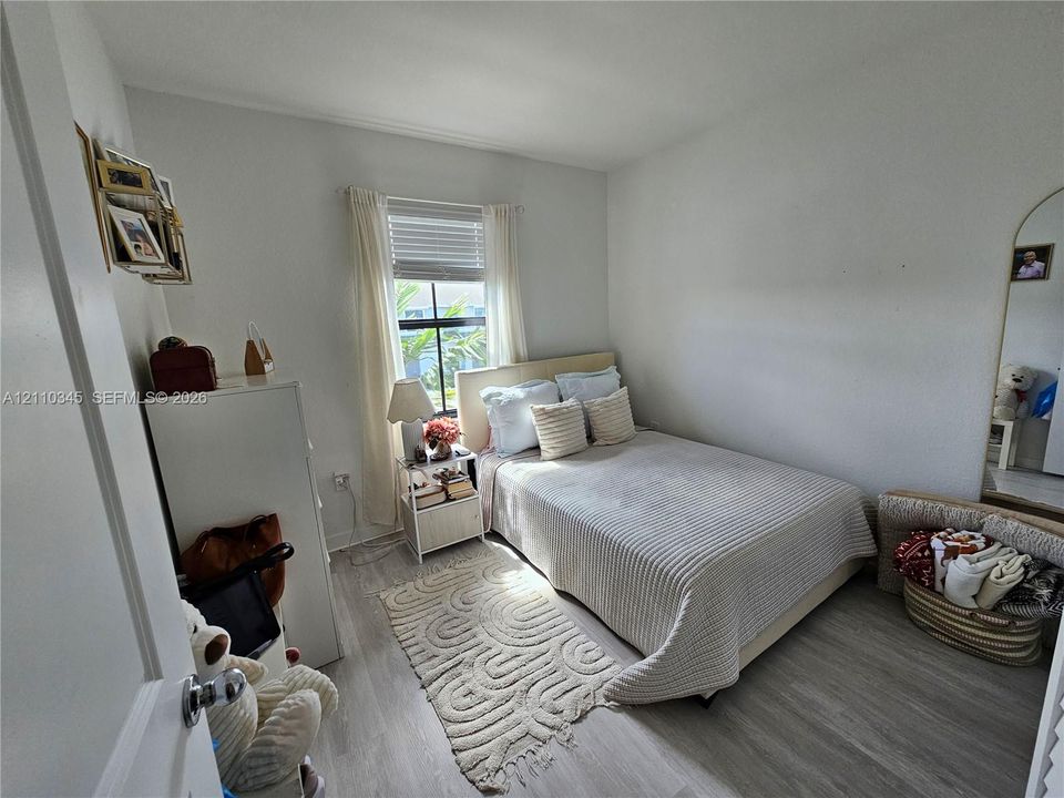 Bedroom featuring light-toned wood-finish flooring, neutral wall paint, and a window with horizontal blinds