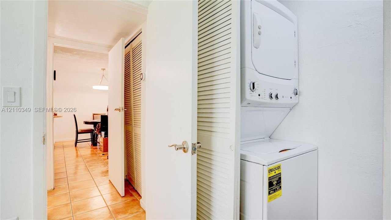 Laundry area featuring a stacked washer and dryer unit and floor-to-ceiling louvered closet doors
