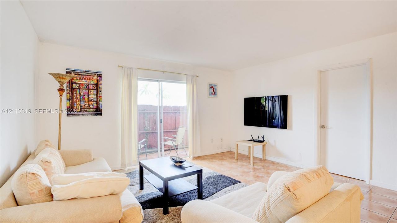 Ceramic tile flooring, white walls, and a sliding glass door providing access to a fenced outdoor area