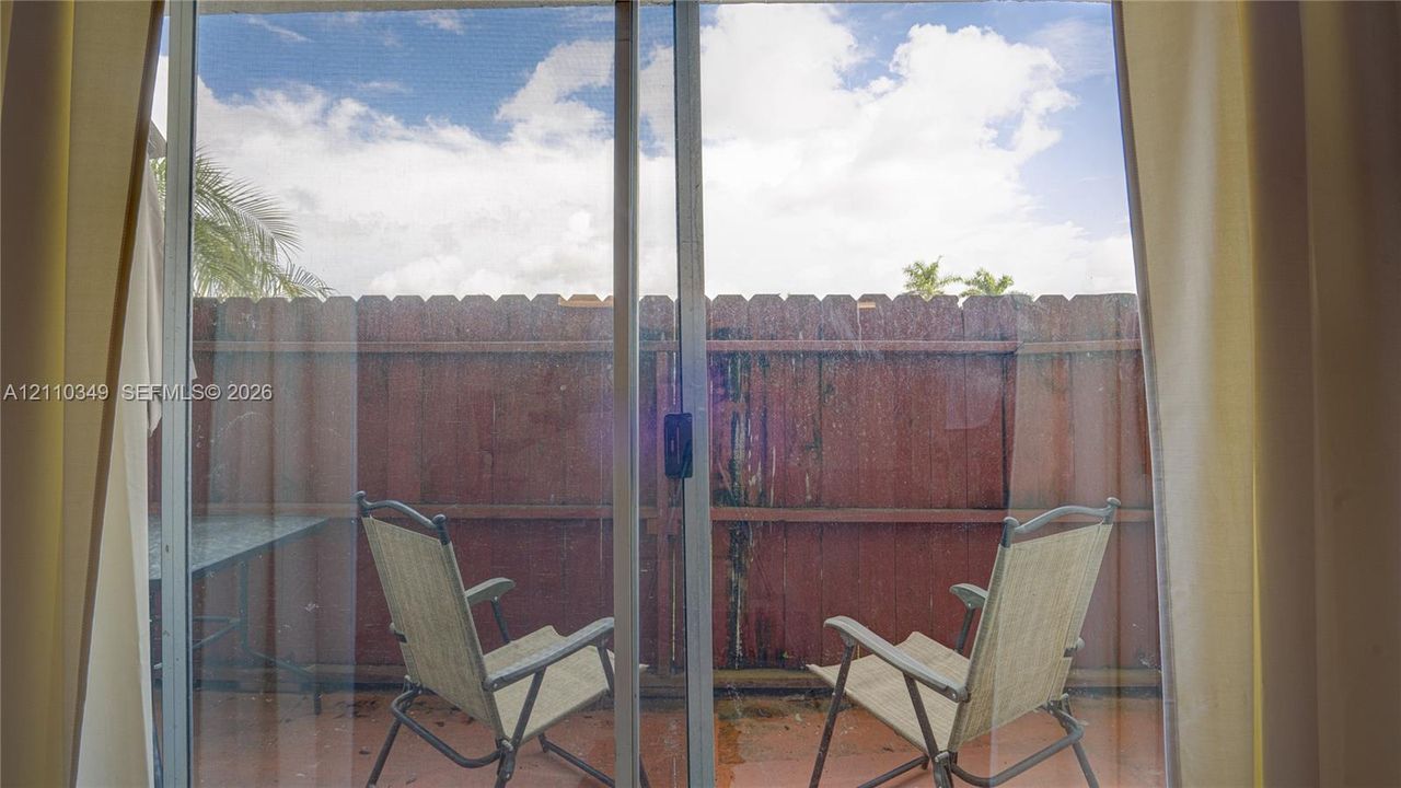 Sliding glass door opening to a paved patio area enclosed by a wood privacy fence