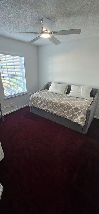 Room featuring deep-toned carpeting, white walls, and a ceiling fan with an integrated light fixture