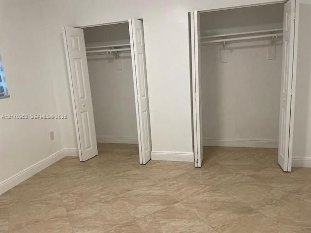 Neutral-toned tile flooring arranged in a diagonal pattern featuring two reach-in closets with bi-fold panel doors and integrated clothing rods