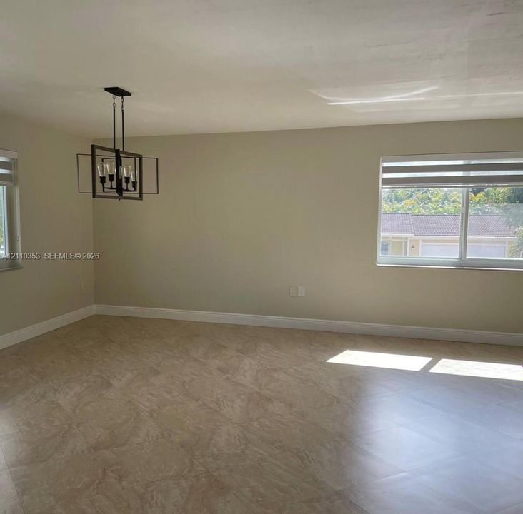 Large-format tile flooring, rectangular double-pane windows, and a black-finish geometric chandelier