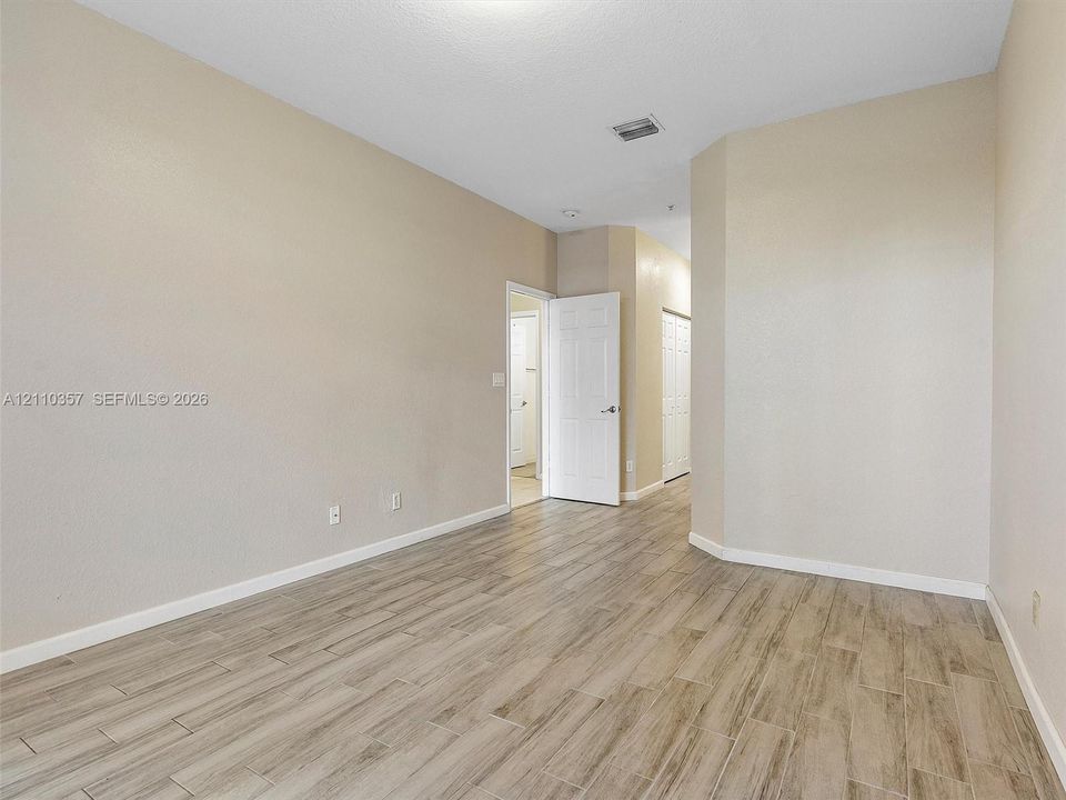 Interior space featuring neutral wall paint, wood-finish flooring, and multiple white interior doors