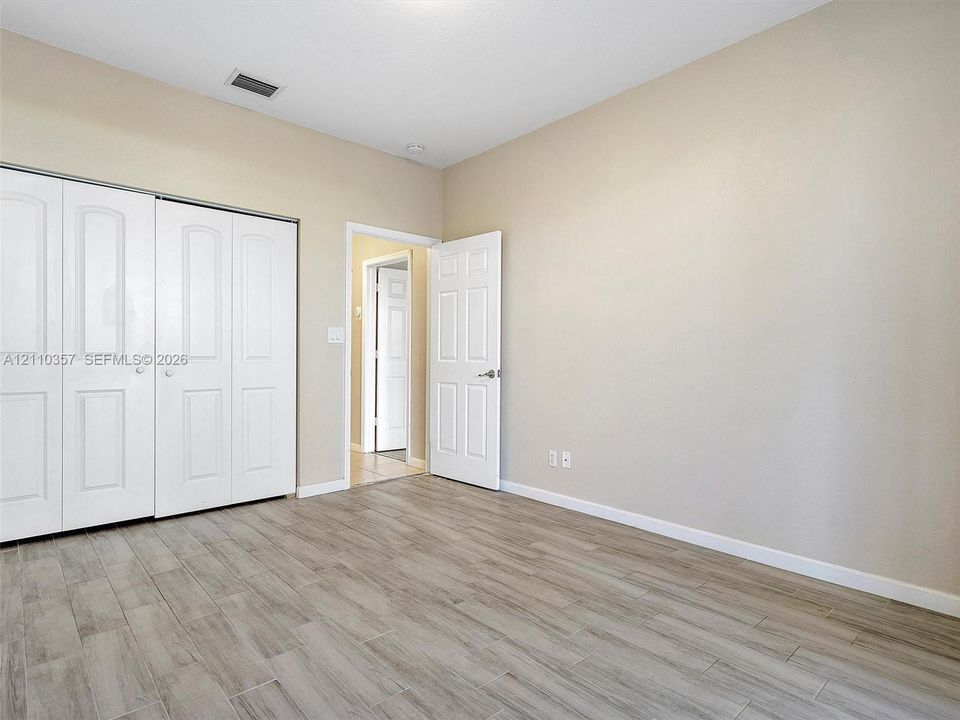Room featuring wood-finish tile flooring, white six-panel interior doors, and built-in bi-fold closet doors