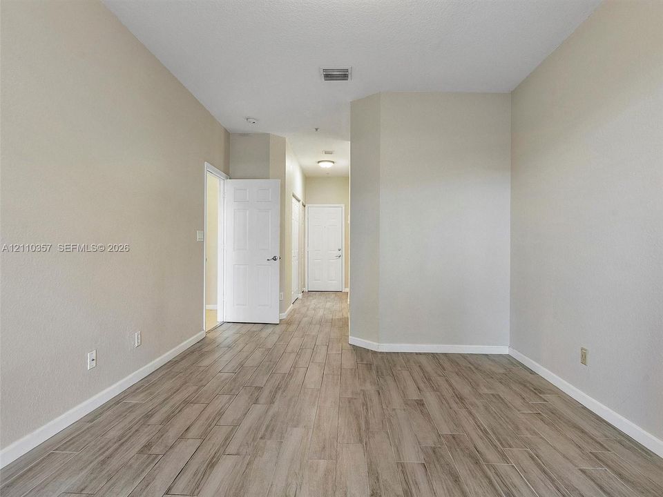 Interior room featuring wood-finish tile flooring, neutral wall paint, and white six-panel interior doors