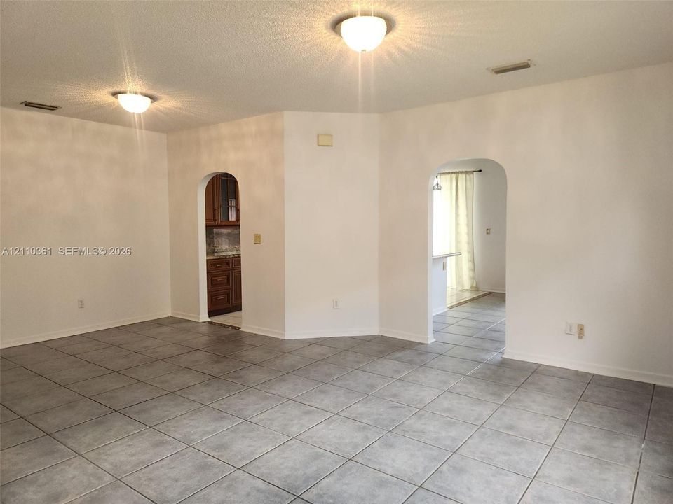 Neutral-toned ceramic tile flooring, arched doorways, and dual flush-mount ceiling light fixtures