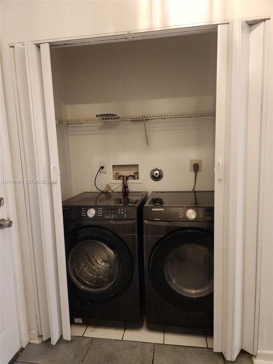 Laundry closet featuring a built-in wire storage shelf, tile flooring, and bi-fold doors