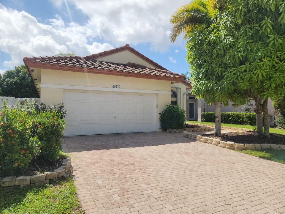 Exterior featuring a paver driveway, tile roofing, and stone-block landscape edging