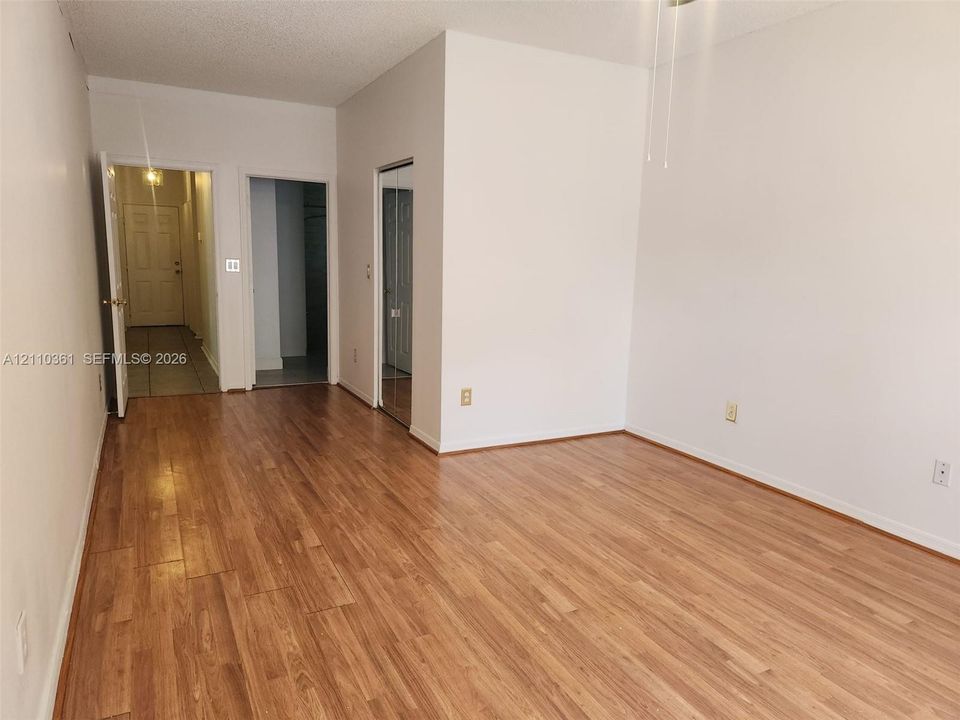 Room featuring wood-finish flooring, mirrored closet doors, and neutral wall paint