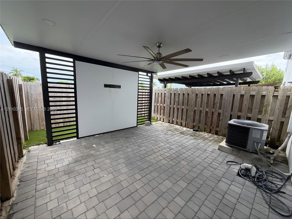 Covered outdoor patio featuring paver flooring, a ceiling fan, recessed lighting, and a slatted privacy screen