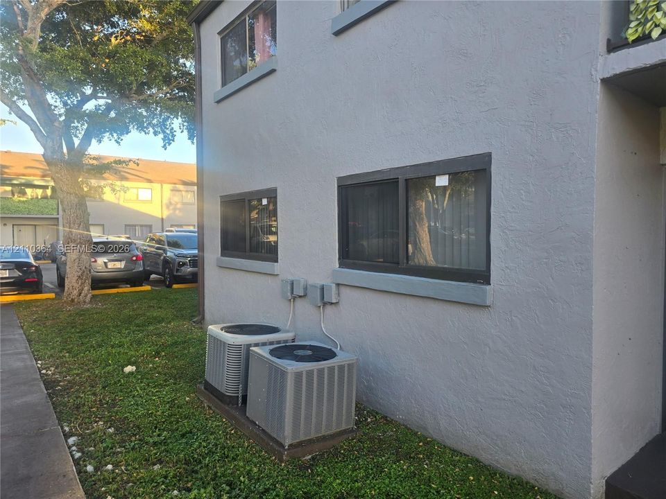 Stucco exterior with sliding windows and dual central air conditioning units