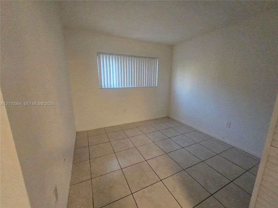 Neutral-toned tile flooring, light-reflective wall surfaces, and horizontal window blinds