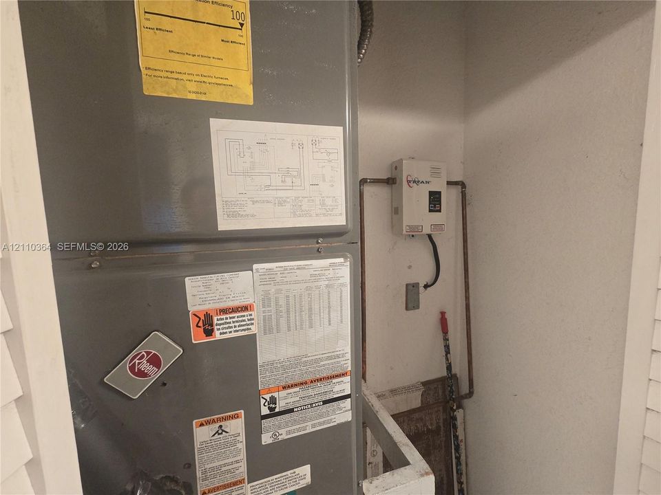 Mechanical closet featuring a Rheem HVAC system and wall-mounted tankless water heater
