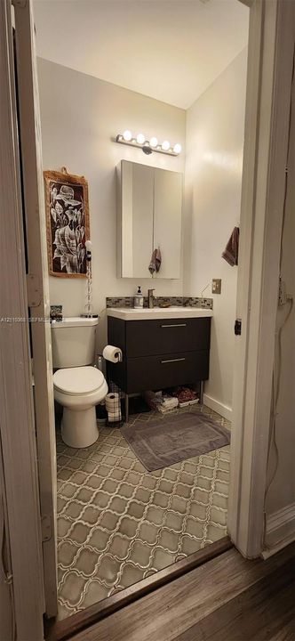 Floating vanity with dual soft-close drawers, integrated rectangular sink, mirrored medicine cabinet, and decorative geometric tile flooring