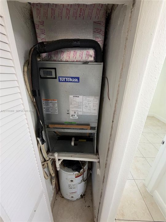 Utility closet housing a vertical air handling unit and a cylindrical water heater