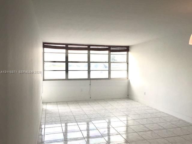 Interior space featuring light-colored tile flooring, smooth wall finishes, and a multi-pane window assembly
