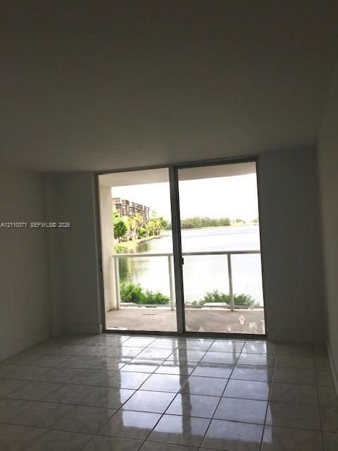 Large-format glass sliding doors opening to a covered balcony with a white metal railing and water frontage