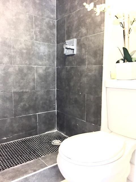 Shower enclosure featuring large-format dark grey wall tile, black penny tile flooring, and a chrome single-handle pressure balance valve