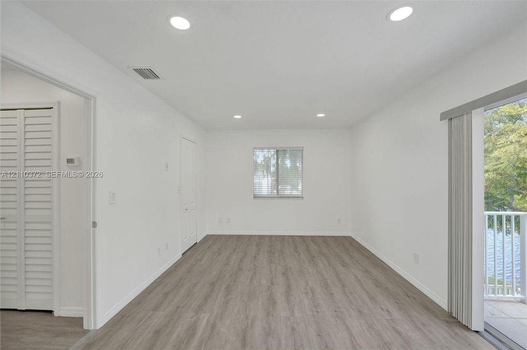 Interior space featuring wood-finish flooring, recessed lighting, a single-pane window, and a sliding glass door providing access to a balcony