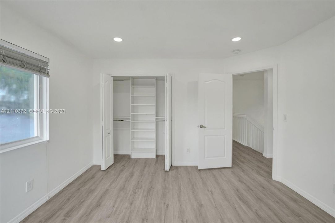 Bedroom featuring wood-finish flooring, recessed lighting, and a closet with built-in shelving