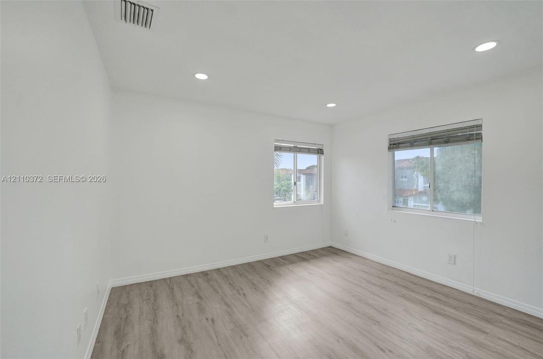 Neutral-toned interior space featuring wood-finish flooring, recessed lighting, and dual windows