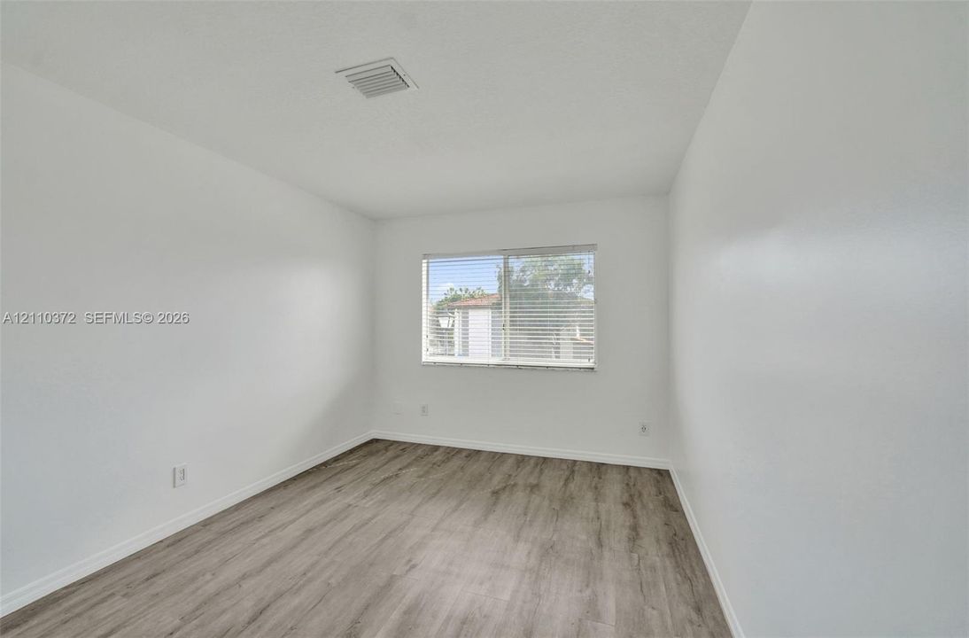 Interior space featuring neutral wall paint and wood-finish flooring with a centered window