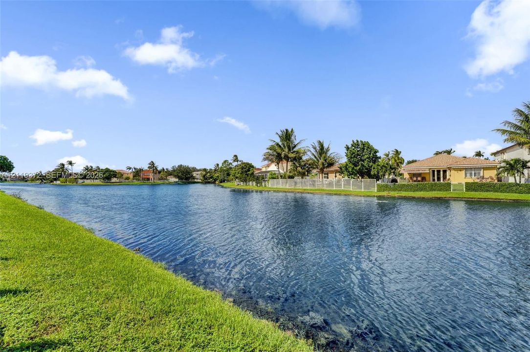 Waterfront lot featuring a manicured lawn, established landscaping, and palm trees