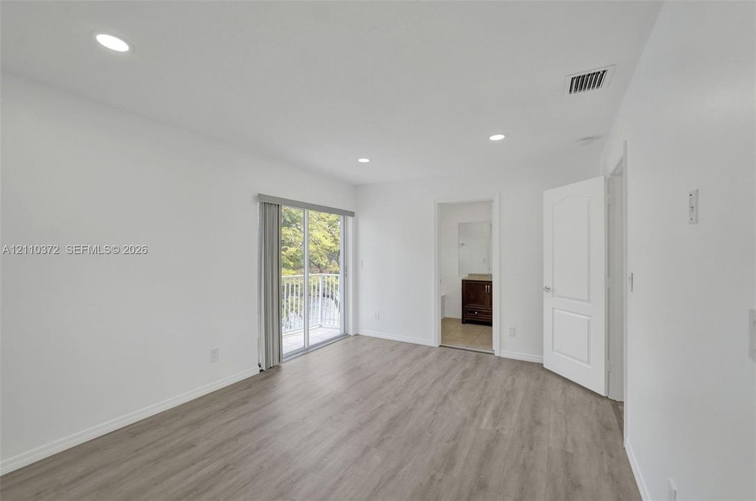 Wood-finish flooring, recessed lighting, and sliding glass doors with balcony access