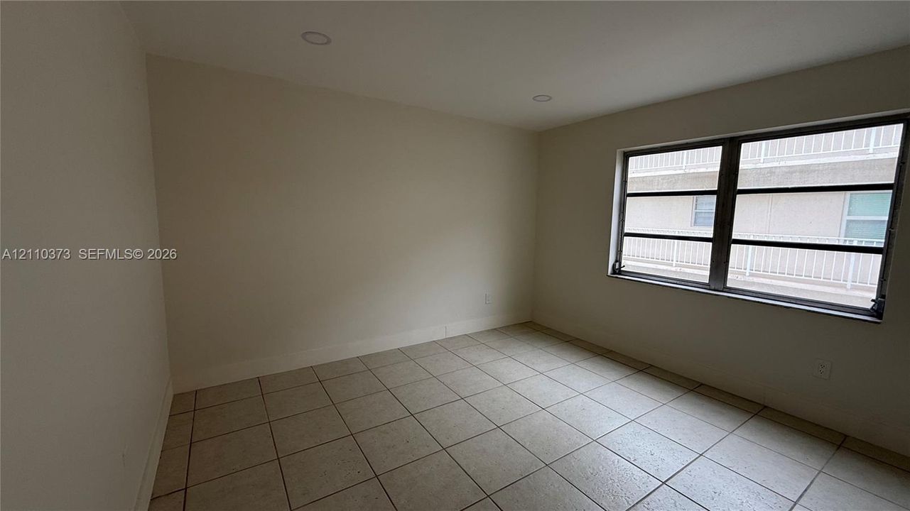 Room featuring neutral-toned ceramic tile flooring, recessed ceiling lighting, and a multi-pane window