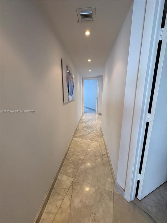 Hallway featuring large-format polished stone tile flooring and recessed ceiling lighting
