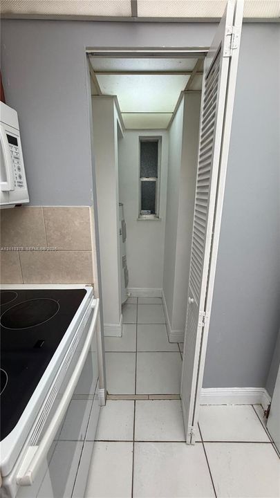 Ceramic tile flooring, louvered closet door, built-in microwave, and stone-finish backsplash