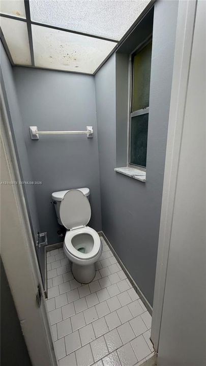 Square tile flooring, opaque panel ceiling light fixture, and window with a stone sill