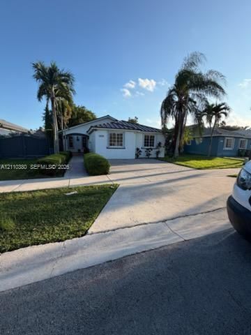 Single-story exterior featuring white stucco siding, a tiled roof, multi-pane windows, and a concrete driveway