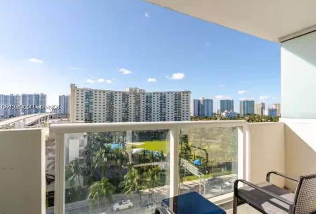 Private balcony featuring glass panel railing and urban skyscape
