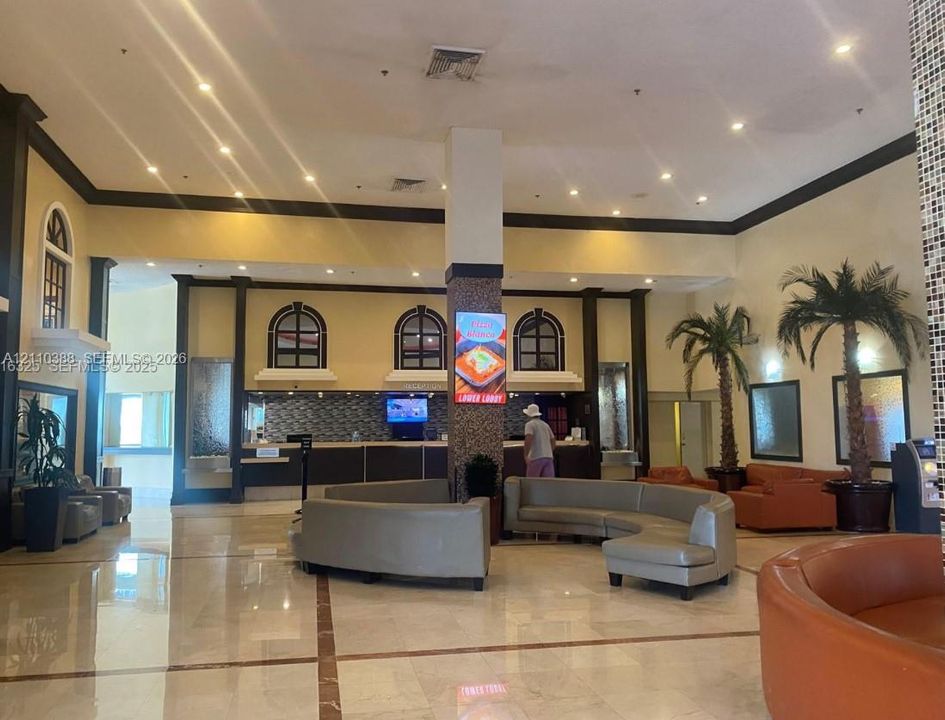 Expansive lobby featuring high ceilings, polished stone tile flooring, recessed lighting, architectural columns, and integrated decorative wall accents