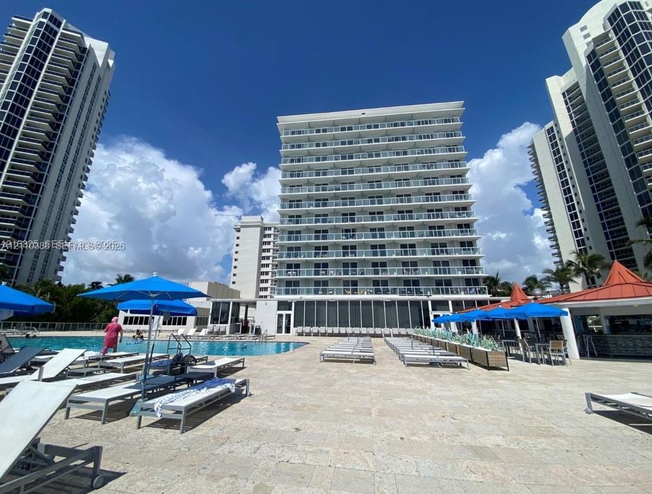 Swimming pool featuring a stone-tile deck and multi-story high-rise architecture with individual recessed balconies