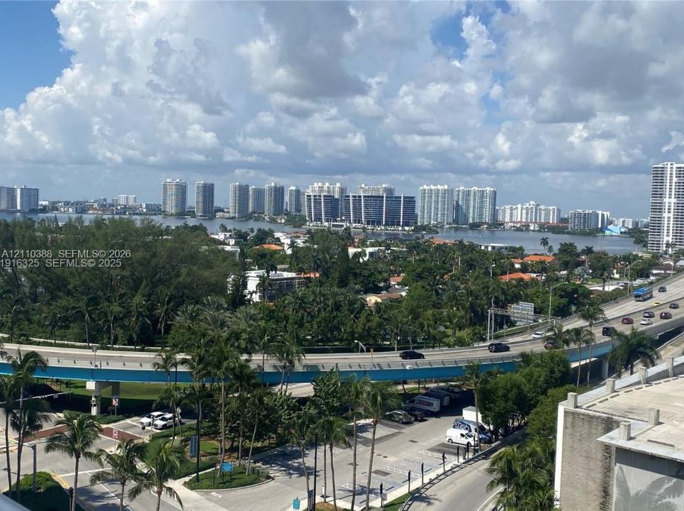 Panoramic cityscape featuring coastal waterway, high-rise buildings, and mature palm trees