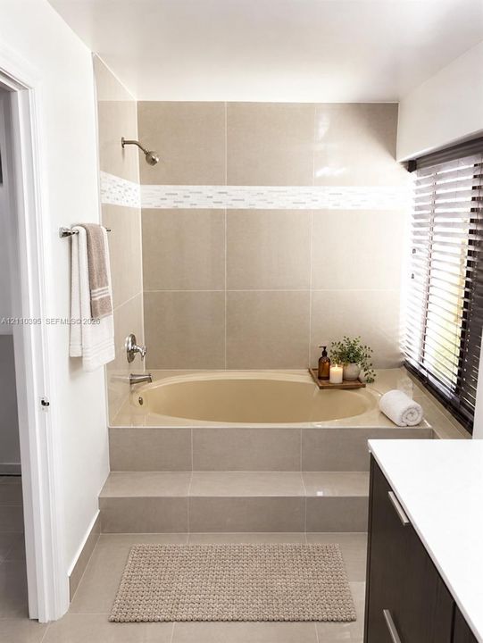 Floating vanity featuring a dark-toned cabinet, integrated countertop with a rectangular basin, large wall-mounted mirror, three-light fixture, and ceramic tile flooring