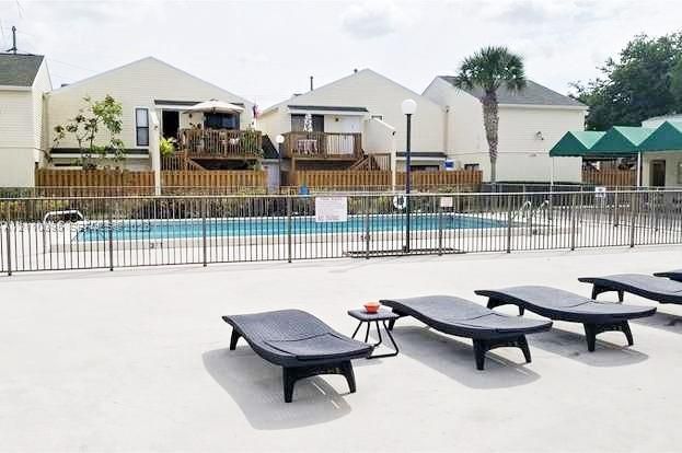 Community swimming pool featuring a concrete deck and metal perimeter fencing