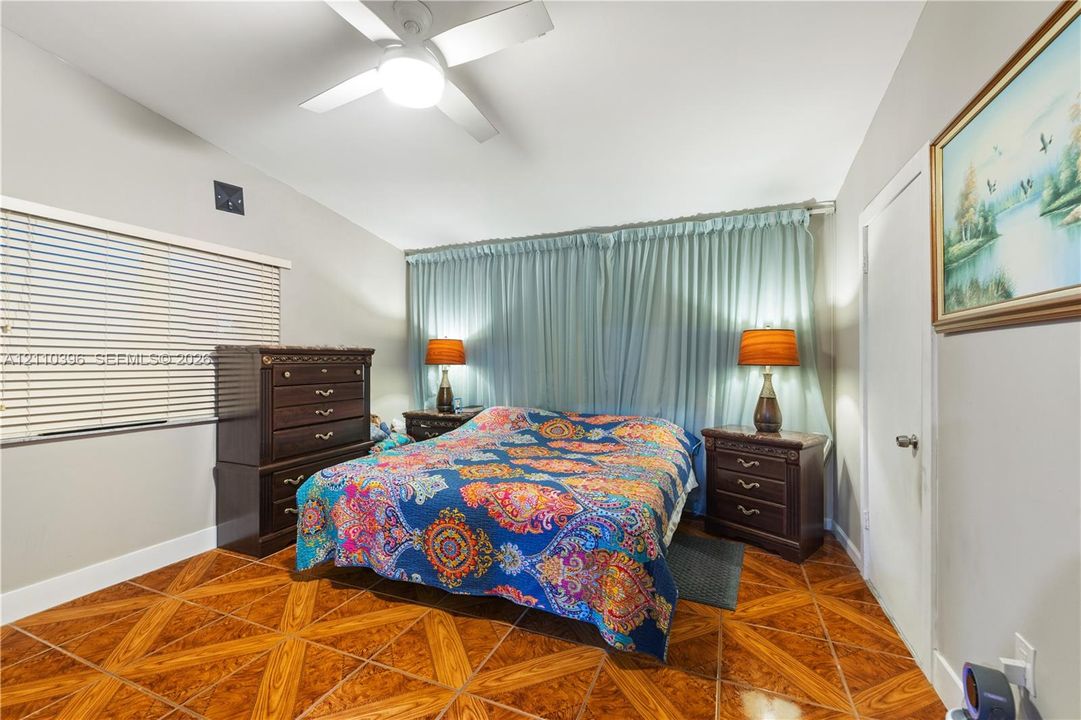 Vaulted ceiling with a white overhead fan, patterned ceramic tile flooring, and horizontal window blinds