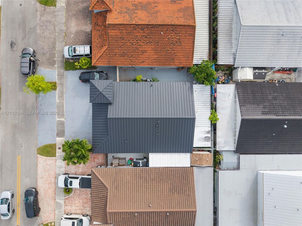 Aerial view of a property featuring a dark-toned standing seam metal roof and a dedicated parking area