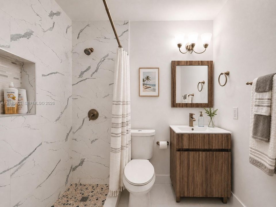 Bathroom featuring a walk-in shower with stone-patterned wall tile, a recessed storage niche, a pebble-finish floor, a wood-finish vanity with a rectangular sink, and a three-light wall-mounted fixture