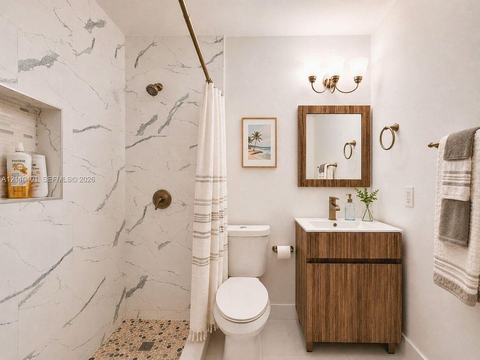 Bathroom featuring a walk-in shower with stone-look wall tile, a pebbled floor, and an integrated wall niche, complemented by a wood-finish vanity and a matching framed wall mirror